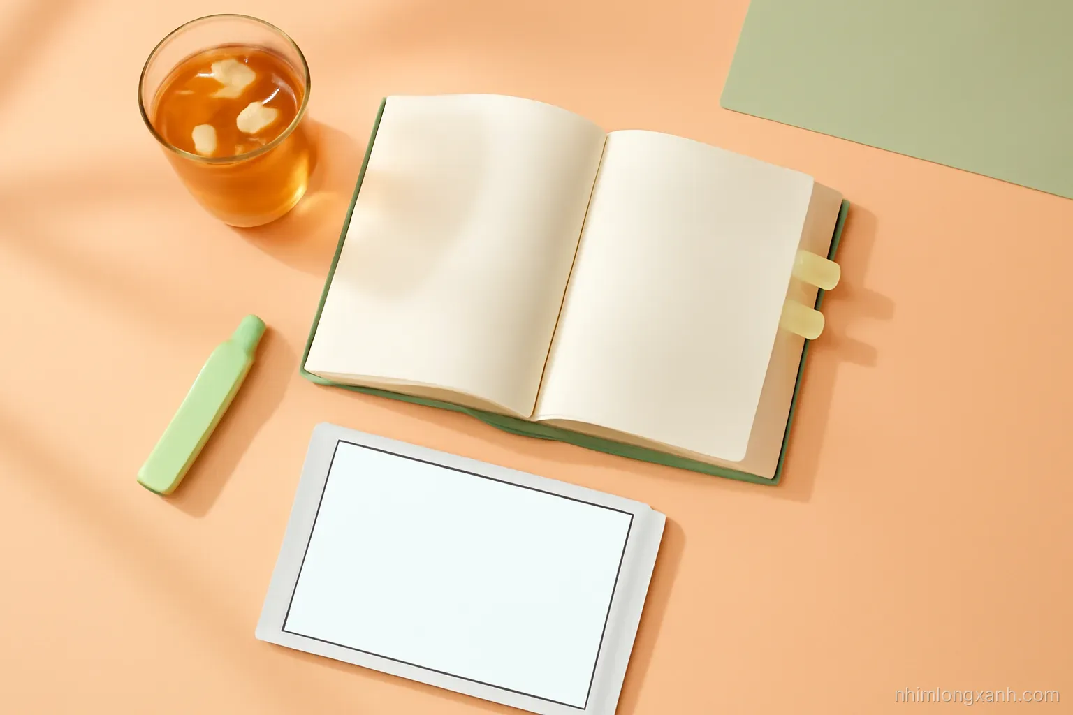 Top-down flat lay of a thick open book with blank pages, sticky tabs, a highlighter, iced tea and a tablet with a blank glowing screen on a peach desk, sage green accents, morning light