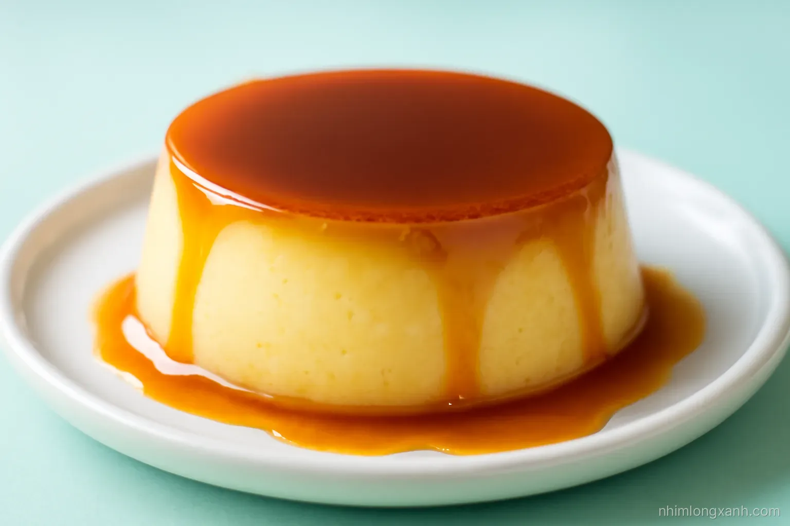 Close-up macro of a glossy Vietnamese caramel custard turned out on a white ceramic plate, amber sauce dripping, soft morning window light, pastel mint background