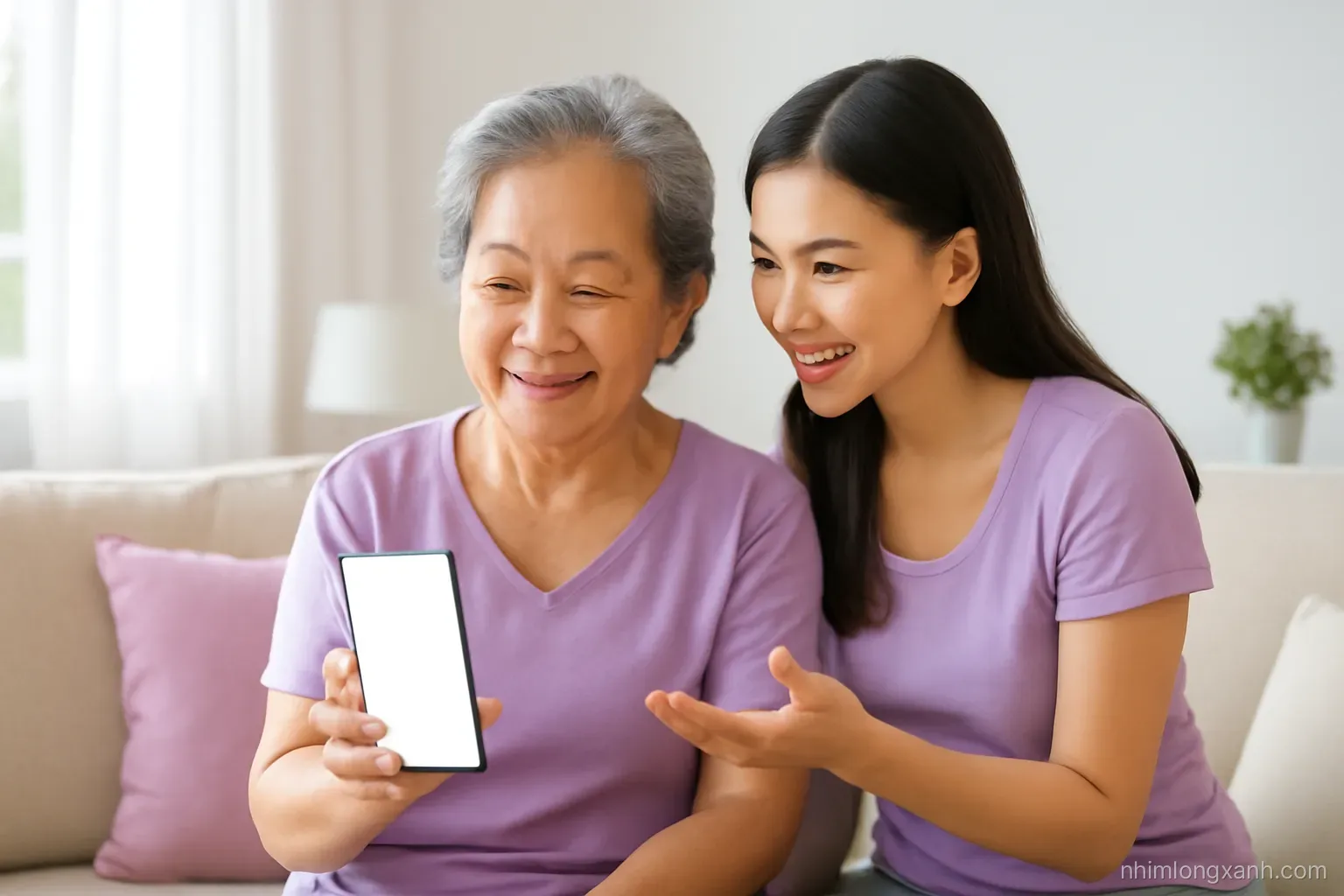 Medium shot of an elderly Vietnamese woman on a sofa holding a smartphone with a blank glowing screen, her granddaughter leaning in to explain, bright living room, lavender and cream palette