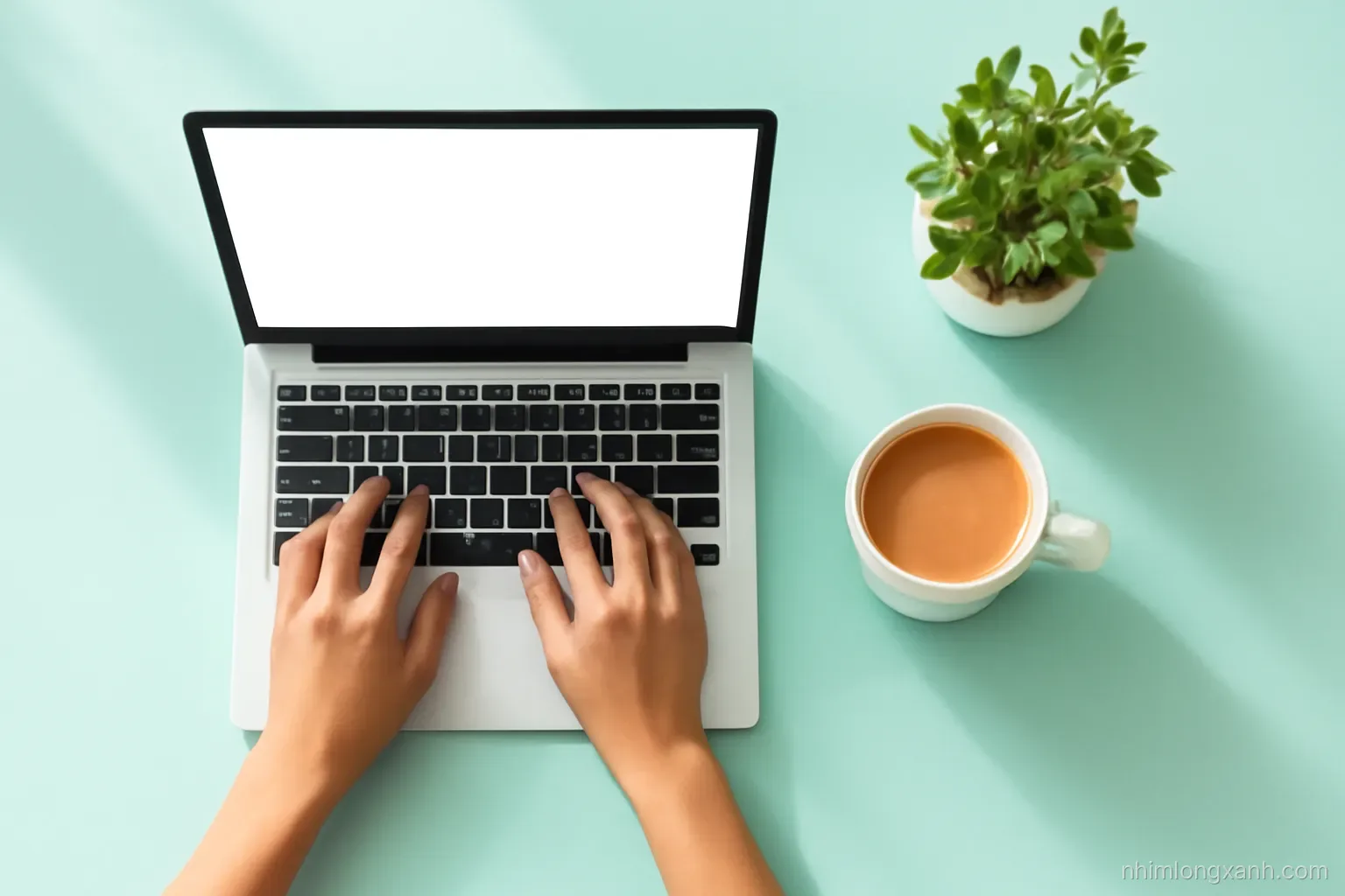 Top-down flat lay of a tidy workspace with a laptop showing a blank glowing screen, a ceramic coffee cup, a green plant and Vietnamese hands typing, crisp daylight, mint and peach palette