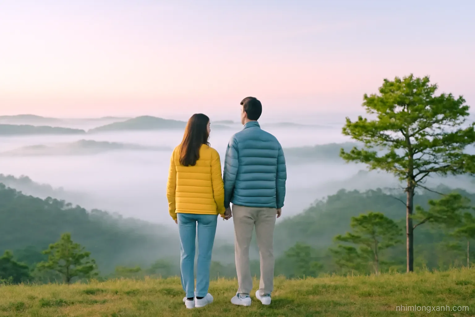 Wide shot at dawn of a Vietnamese couple in puffer jackets standing on a pine hill above a sea of white clouds, soft pink sky, misty green valley, cool pastel tones