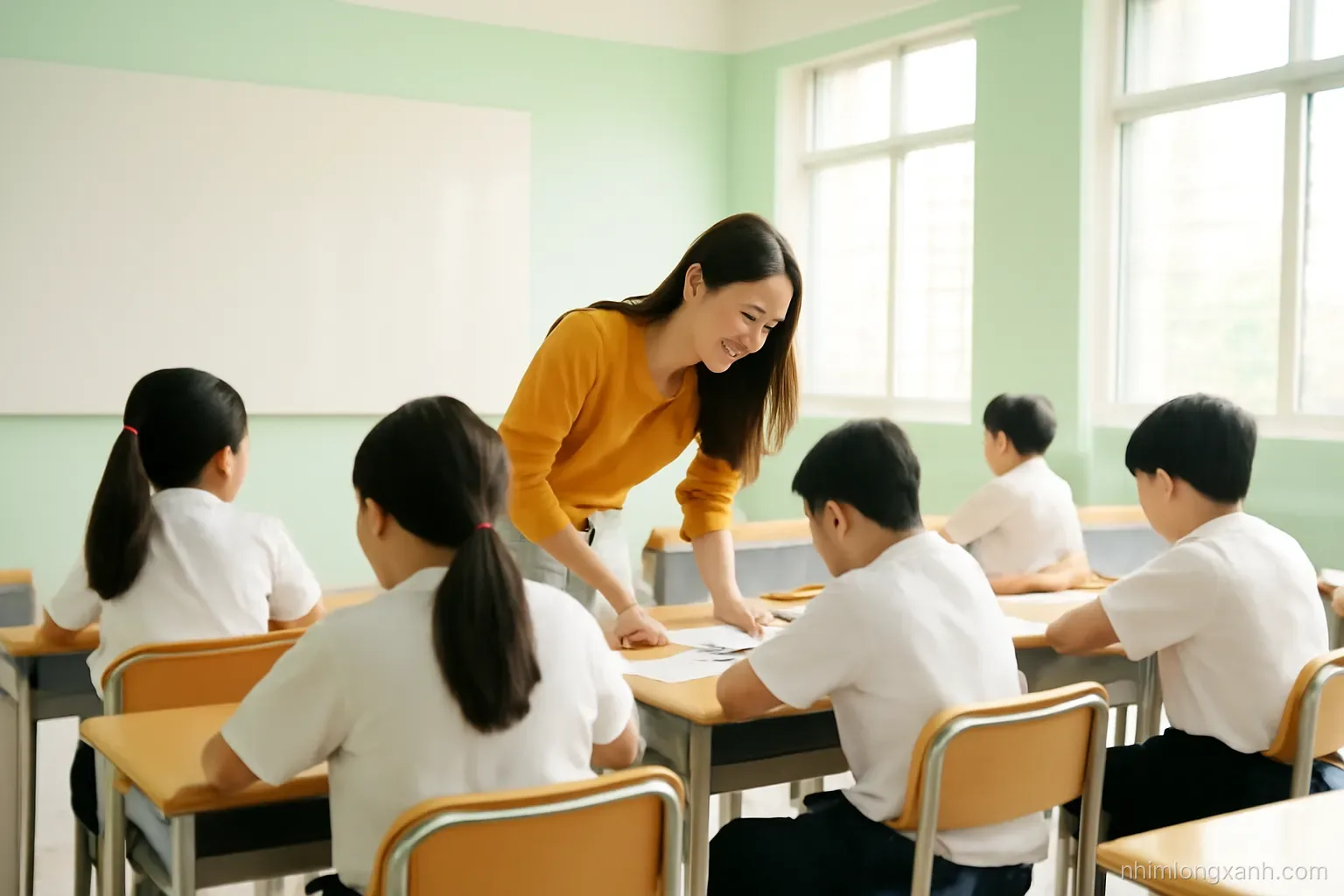 Wide shot from the back of a bright Vietnamese secondary classroom, young female teacher walking between desks bending to help a student, students in white uniforms, sunlight through windows, soft green walls