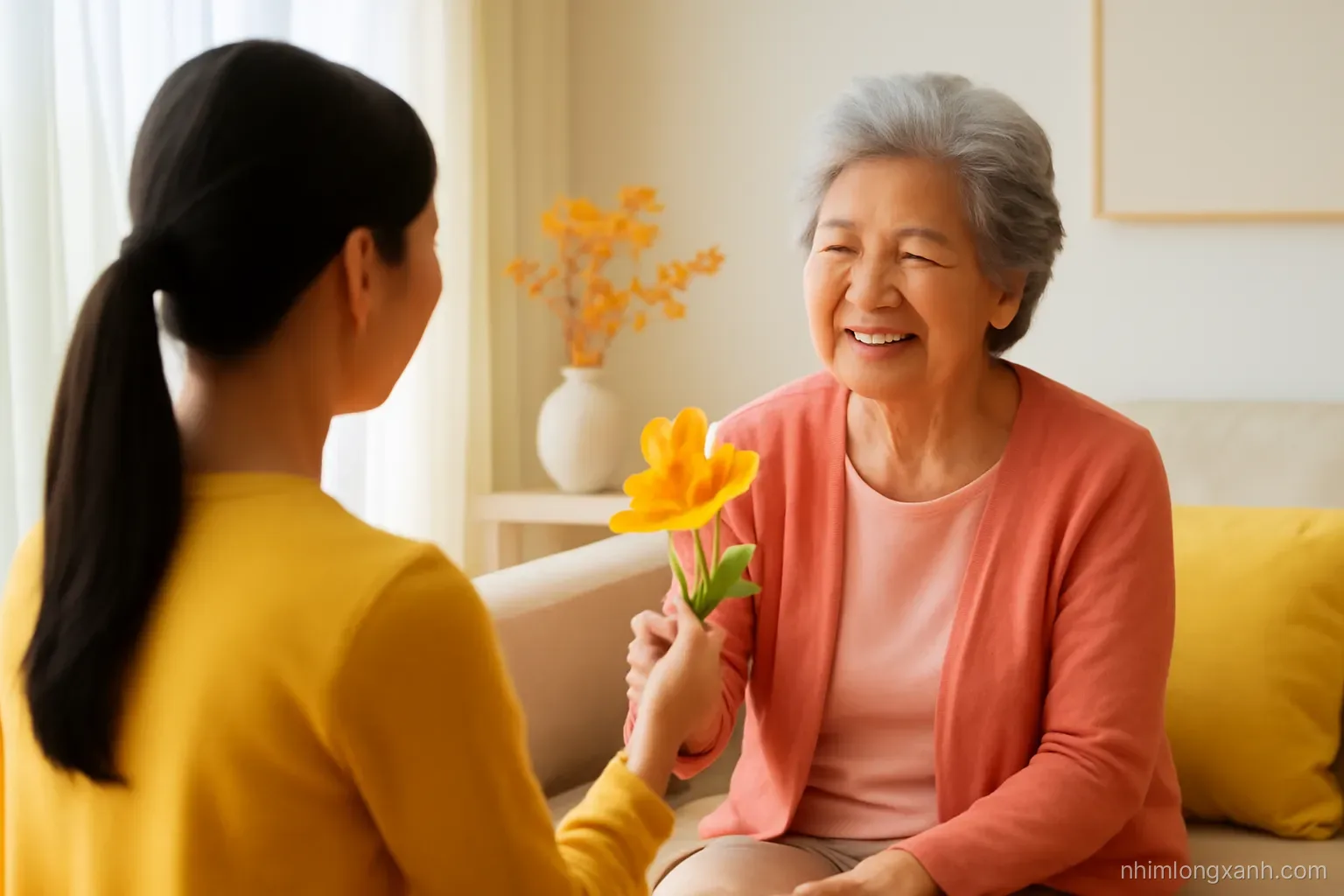 Over-the-shoulder view of a Vietnamese girl handing a homemade paper flower to her grandmother in a sunlit living room, autumn yellow and soft coral tones