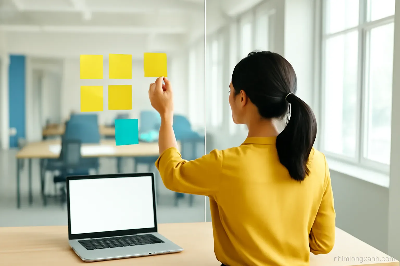 Over-the-shoulder shot of a Vietnamese office worker sorting colorful sticky notes into two groups on a glass wall, blank laptop glowing on desk, airy coworking space, lemon yellow and slate blue palette