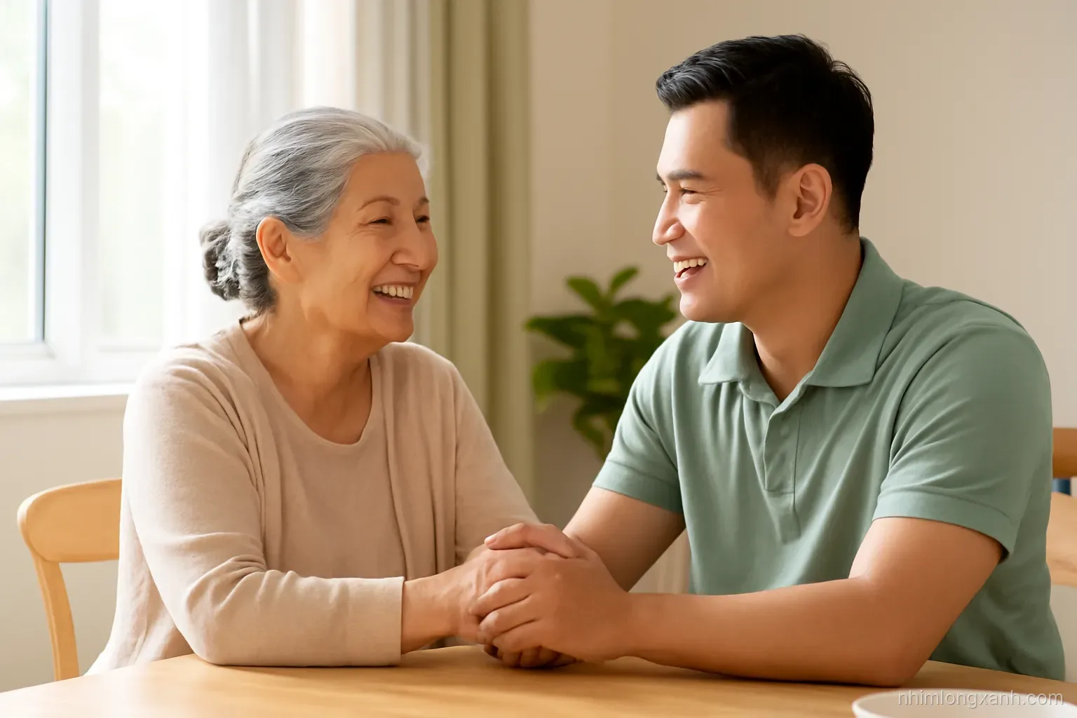 Elderly Vietnamese grandmother and adult son sitting at a wooden dining table, holding hands, warm afternoon window light, soft beige and green tones, medium shot from the side
