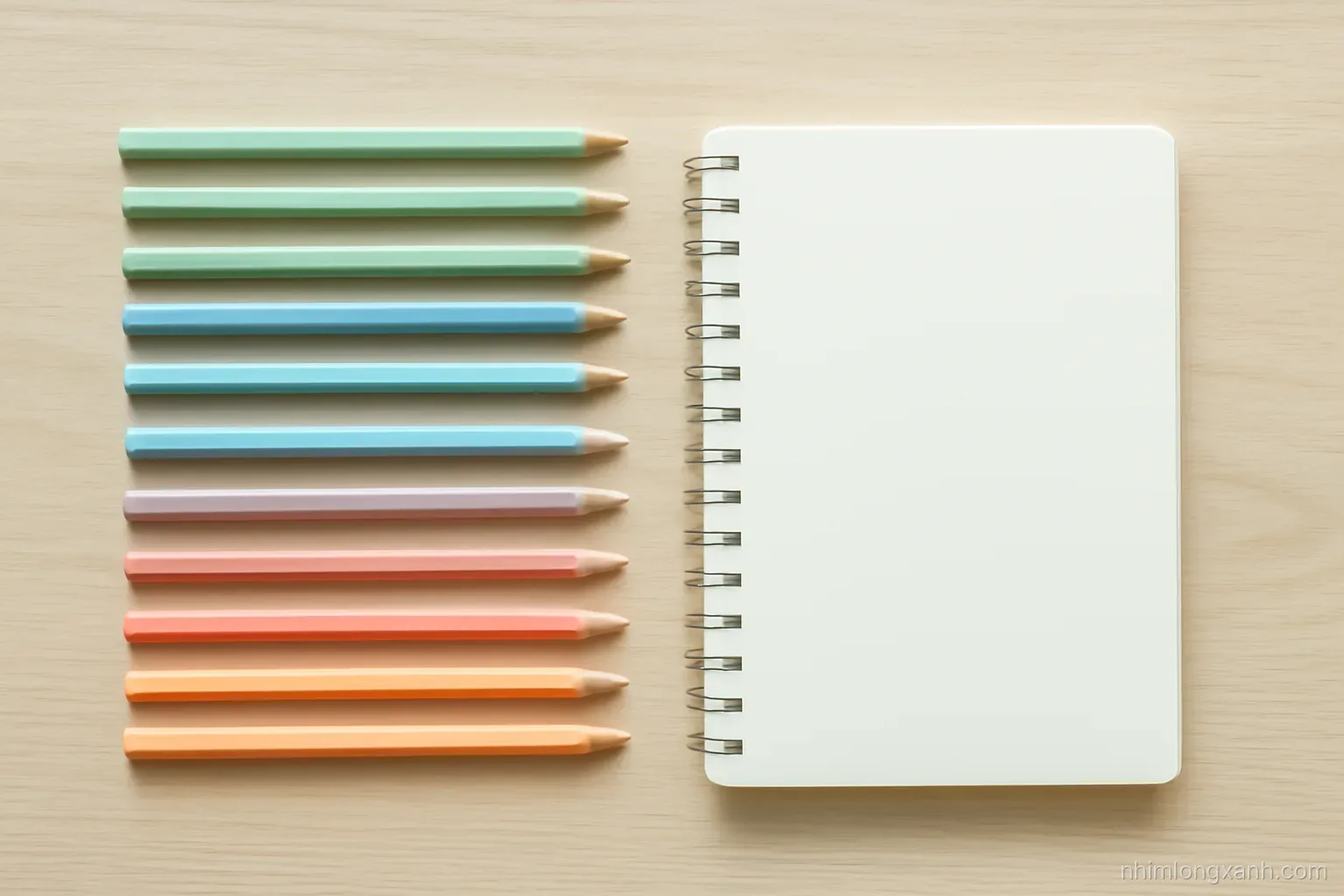 Top-down flat lay of colorful pencils, an eraser and a blank notebook arranged in neat rows on a pale oak desk, soft morning light, pastel mint and peach palette