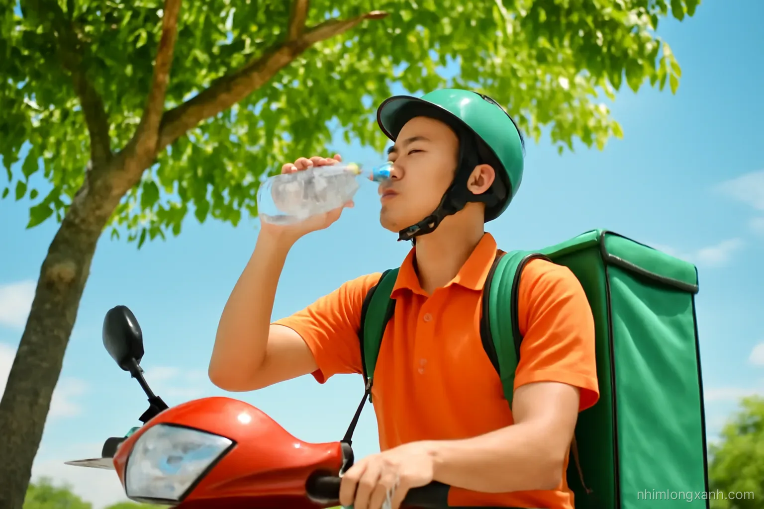 Slightly high angle medium shot of a Vietnamese delivery rider resting under a leafy tree, drinking from a water bottle on a bright summer noon, vivid blue sky, fresh green and orange tones