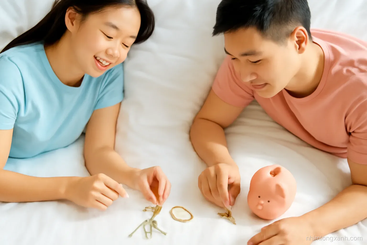 Young Vietnamese couple sorting keys, gold bracelet and a piggy bank on a white bed, top-down flat lay, bright morning light, pastel blue and peach palette