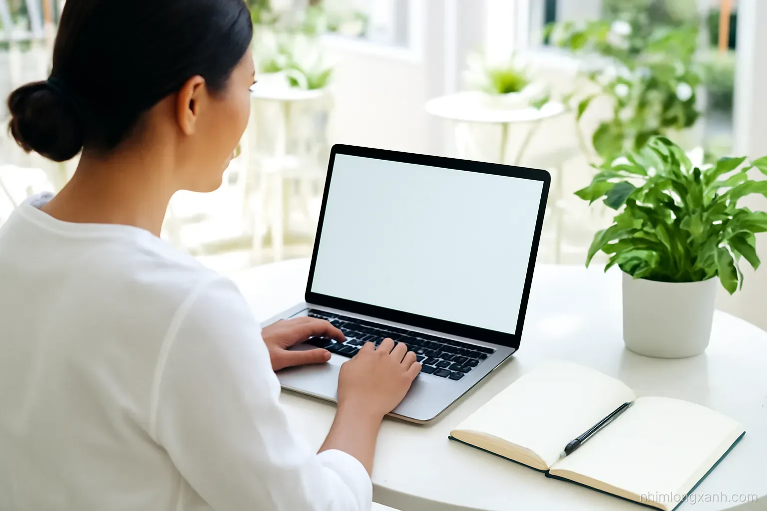 Wide shot of a young Vietnamese couple packing online orders into plain kraft boxes on a long table in a bright home shop, laptop with blank glowing screen, fresh green and white palette