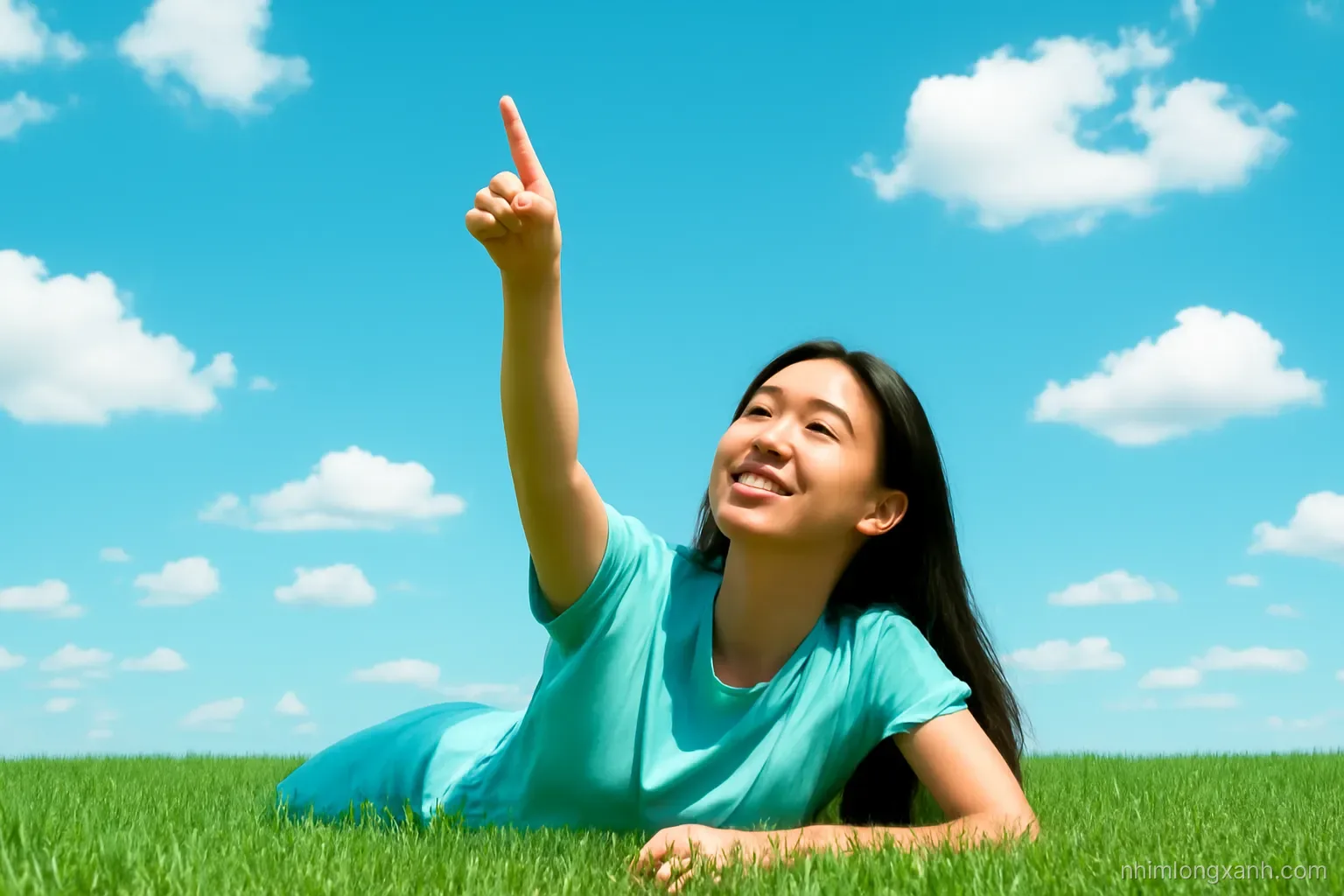 Low angle wide shot of a Vietnamese girl lying on fresh green grass pointing up at a vivid blue sky with scattered white clouds, bright midday light, cyan and green palette