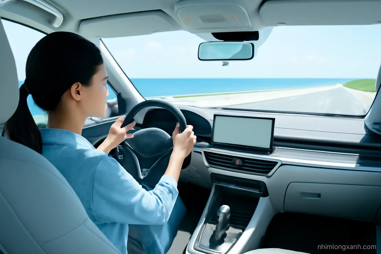 Wide shot from the back seat, a Vietnamese woman driver resting both hands lightly on the steering wheel on an empty coastal highway, bright midday light, silver and sea blue palette